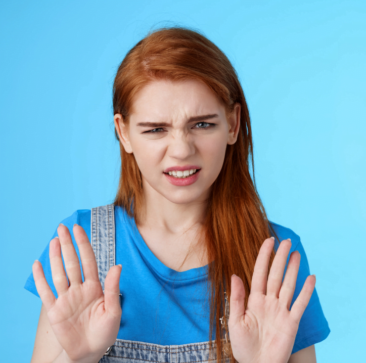 young woman with krinkled nose putting her hands up in a "no" gesture